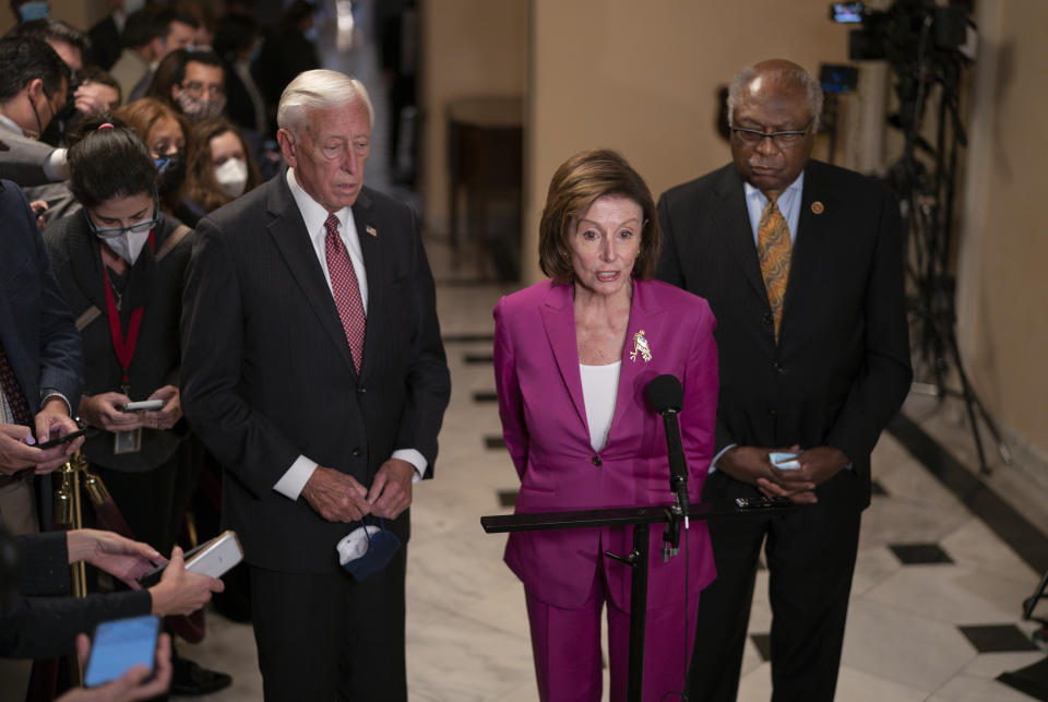 Nancy Pelosi stands at a podium, flanked by House Majority Leader Steny Hoyer and House Majority Whip Jim Clyburn.
