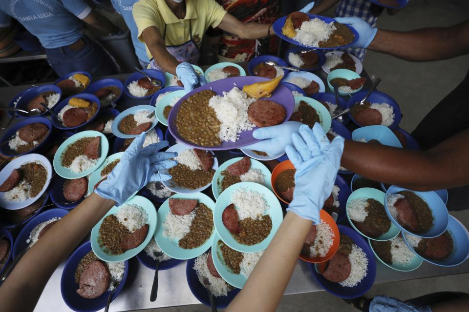 Volunteers prep free lunch plates with lentils, a slice of bologna, rice and a piece of plantain at the "Divina Providencia" migrant shelter in La Parada, near Cucuta, Colombia, on the border with Venezuela, Monday, Feb. 18, 2019. The director of the shelter says they serve about 4,500 lunches per day, mostly to Venezuelan migrants, everyday of the week with the exception of Sunday. (AP Photo/Fernando Vergara)