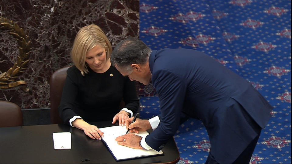 In this image from video, Sen. Mitt Romney, R-Utah, signs the oath book after being sworn in for the impeachment trial of President Donald Trump in the Senate at the U.S. Capitol in Washington, Thursday, Jan. 16, 2020. (Senate Television via AP)