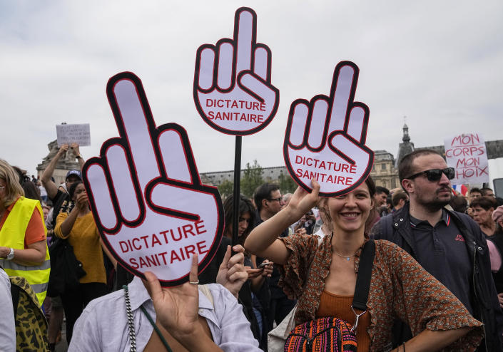 Anti-vaccine protesters hold placard that reads health dictatorship during a rally in Paris, Saturday, July 17, 2021. Tens of thousands of people protested across France on Saturday against the government's latest measures to curb rising COVID-19 infections and drive up vaccinations in the country. (AP Photo/Michel Euler)
