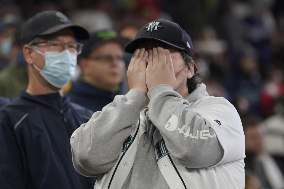 A Seattle Mariners fan reacts after Los Angeles Angels' Jack Mayfield was ruled safe stealing second base after the initial call of out was overturned on review during the sixth inning of a baseball game, Sunday, Oct. 3, 2021, in Seattle. (AP Photo/Ted S. Warren)