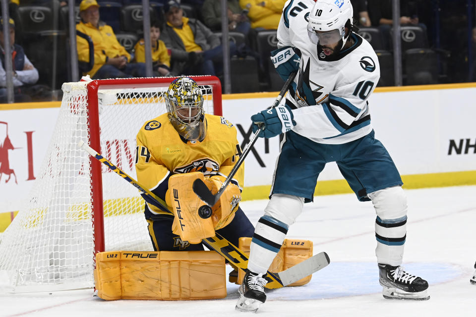 San Jose Sharks left wing Anthony Duclair (10) tries to deflect a shot towards Nashville Predators goaltender Juuse Saros (74) during the first period of an NHL hockey game Saturday, Oct. 21, 2023, in Nashville, Tenn. (AP Photo/Mark Zaleski)