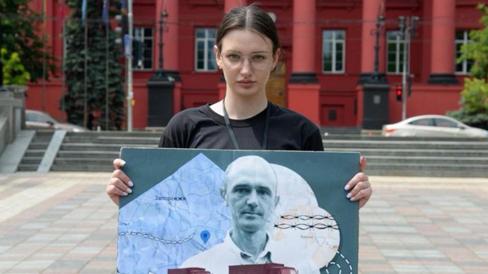 PHOTO: Yulia Khrypun, 22, holds a poster with a photo of her father, Serhiy, who was taken into Russian captivity while working as a security officer at a farm in a village in Ukraine's Zaporizhzhia region. (Yulia Khrypun)