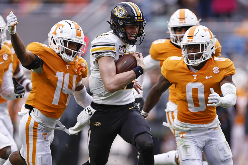 Missouri quarterback Brady Cook (12) runs for yardage as he is chased by Tennessee defensive back Doneiko Slaughter (0), and defensive back Christian Charles (14) during the first half of an NCAA college football game Saturday, Nov. 12, 2022, in Knoxville, Tenn. (AP Photo/Wade Payne)