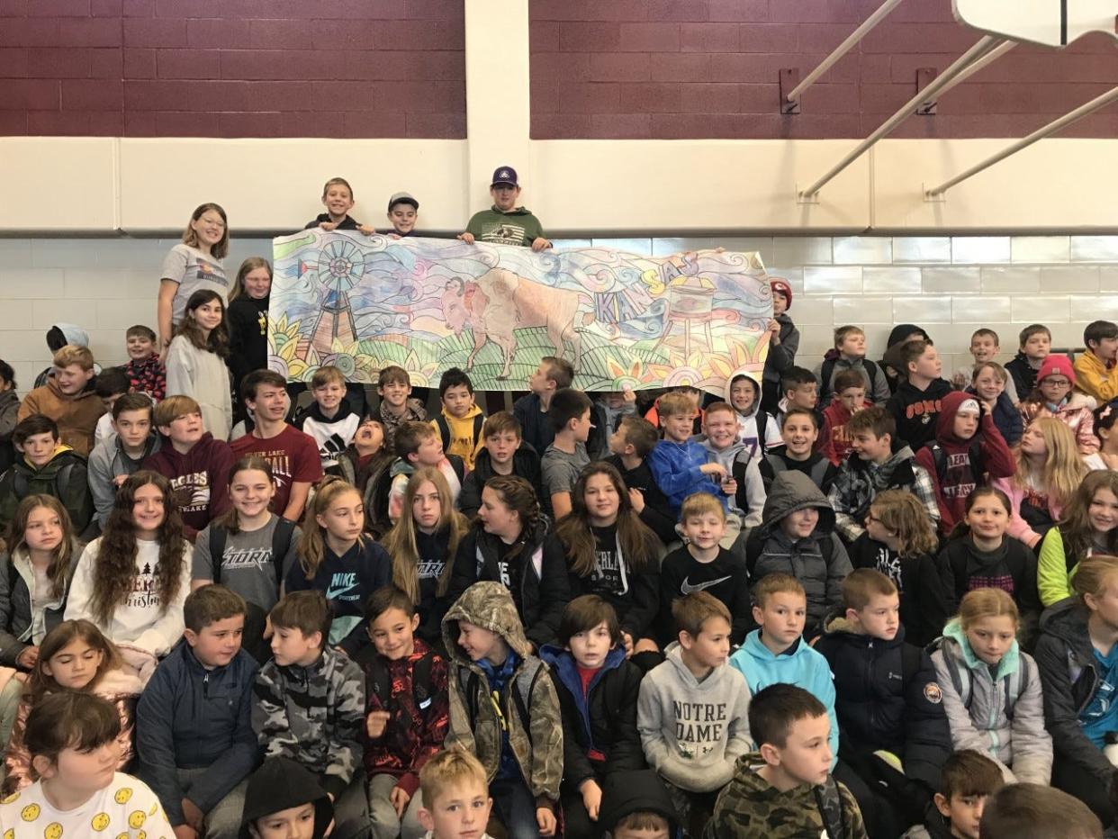 Second- through sixth-grade Silver Lake Elementary School students pose with the traveling mural, designed by high school students, that they helped color.