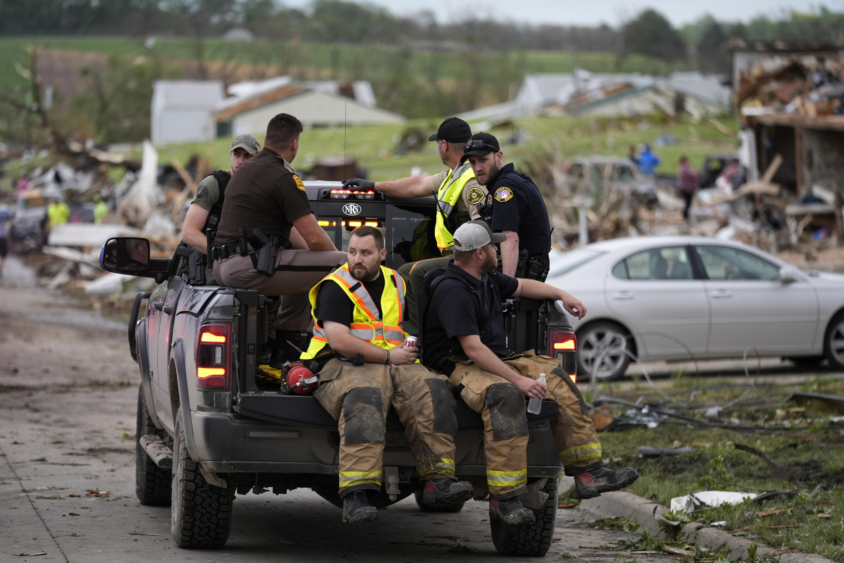 Law enforcement officers and firefighters ride in a truck past homes destroyed by a tornado on Tuesday in Greenfield, Iowa. 