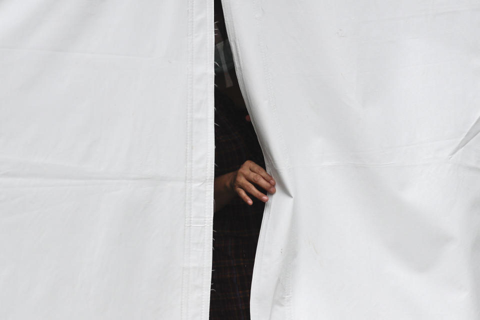 A COVID-19 patient looks out from their isolation tent outside a hospital as cases increase in Manila, Philippines on Monday, April 26, 2021. COVID-19 infections in the Philippines surged past 1 million Monday in the latest grim milestone as officials assessed whether to extend a monthlong lockdown in Manila and outlying provinces amid a deadly spike or relax it to fight recession, joblessness and hunger. (AP Photo/Aaron Favila)