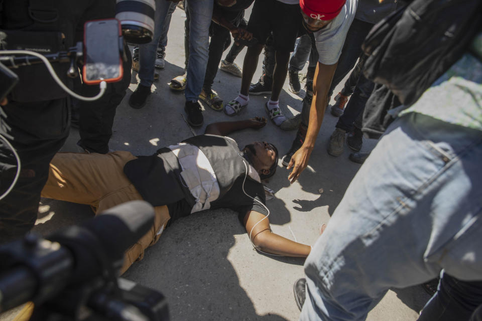 CONFIRMS DEATH OF PHOTOJOURNALIST - Haitian photojournalist Maxihen Lazzare lies dead on the ground, after he was shot while covering a protest by factory workers demanding higher salaries in Port-au-Prince, Haiti, Wednesday, Feb. 23, 2022. Men wearing police uniforms drove by the protest and fired into the crowd of protesters where Lazzare was covering the demonstration. (AP Photo/Odelyn Joseph)