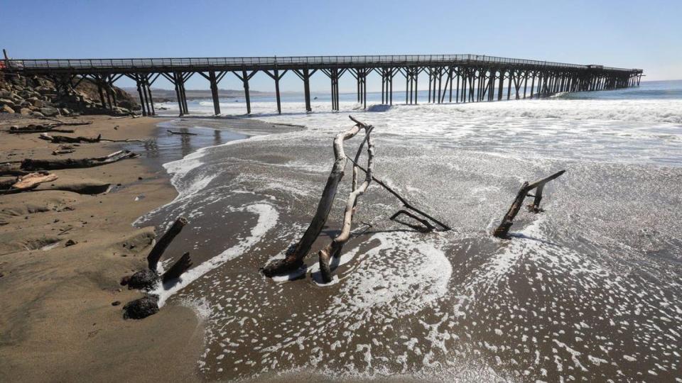 Driftwood is stuck in sand as waves crash. San Simeon Pier is closed due to wave damage Oct. 17, 2023.