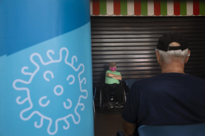FILE - Men are seated after receiving the a third Pfizer-BioNTech COVID-19 vaccine at a coronavirus vaccination center in Tel Aviv, Israel, Tuesday, Aug. 10, 2021. The coronavirus's omicron variant kept a jittery world off-kilter Wednesday Dec. 1, 2021, as reports of infections linked to the mutant strain cropped up in more parts of the globe, and one official said that the wait for more information on its dangers felt like “an eternity.” (AP Photo/Oded Balilty, File)