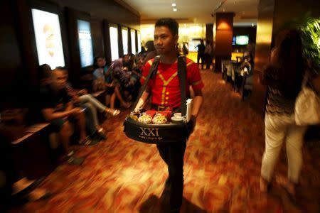 An employee of Cinema 21 Group carries snack and drinks to sell inside a theater at Djakarta Theater in Jakarta, Indonesia, February 18, 2016. REUTERS/Beawiharta