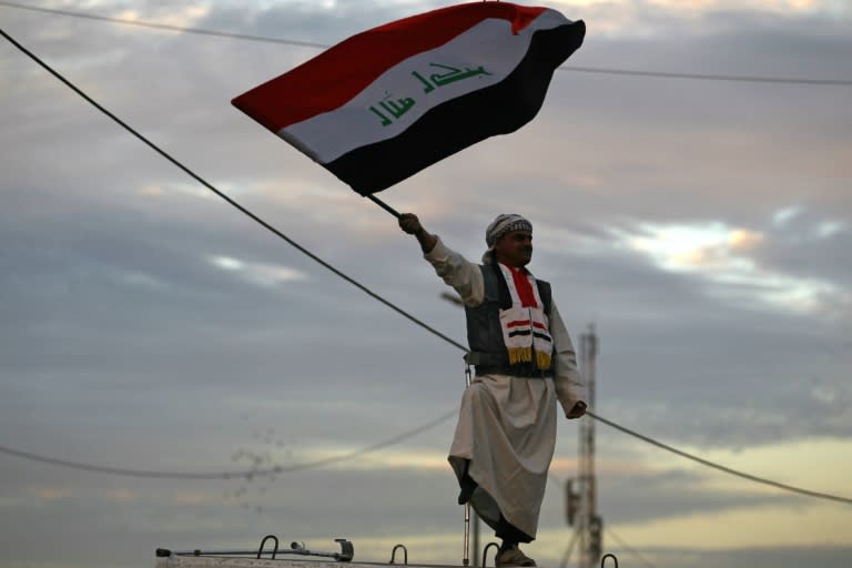 An Iraqi man waving the national flag in Baghdad to celebrate the end of the three-year war against the Islamic State group in December 2017 -- but experts warn IS is far from defeated and already morphing into a dangerous underground organization