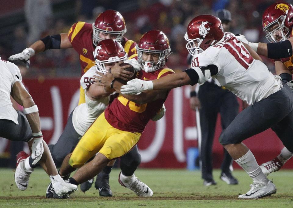 USC running back Travis Dye is tackled by Washington State defensive end Andrew Edson.