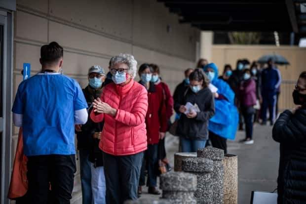 People are pictured lined up to receive their COVID-19 vaccination at a clinic in the Fraser Health region of Surrey, B.C., on Tuesday.