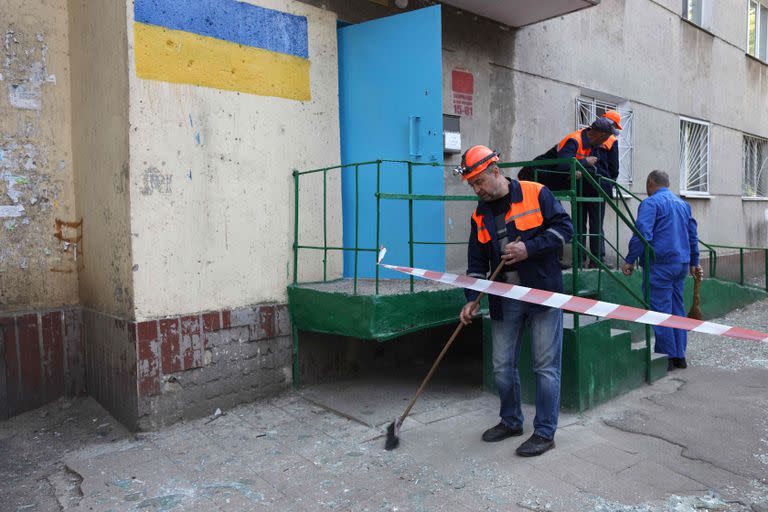 Trabajadores municipales limpian los cristales rotos y los escombros frente a un edificio residencial junto al lugar donde se produjo un ataque con misiles rusos en la ciudad de Odessa, en el sur de Ucrania, el 7 de mayo de 2022