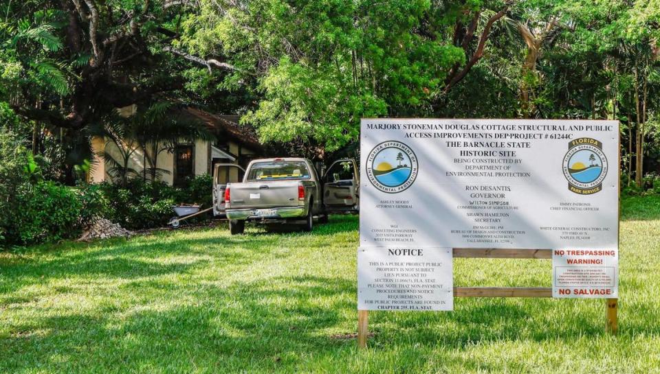 La camioneta de un contratista afuera de la cabaña de Marjory Stoneman Douglas en Coconut Grove, donde un cartel colocado por el estado describe los esfuerzos de restauración en curso.