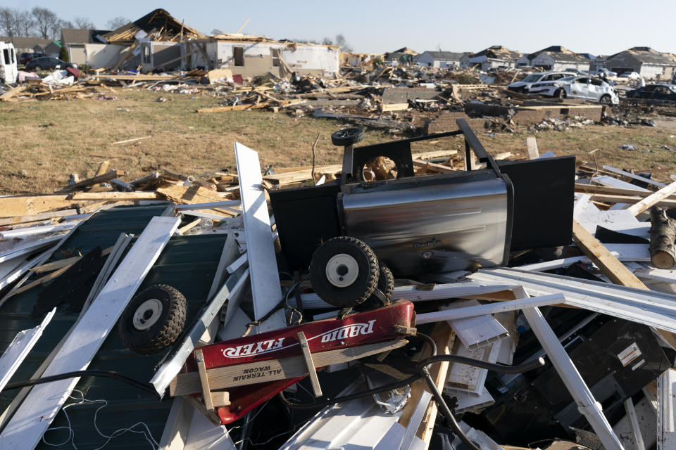 A Radio Flyer wagon lies among debris along Moss Creek Avenue Tuesday, Dec. 14, 2021, in Bowling Green, Ky. When a tornado touched down in Bowling Green in the middle of the night, its violence was centered on a friendly subdivision. Fourteen people died in a few blocks, 11 of them on Moss Creek Avenue. Entire families were lost, between them seven children, two of them infants. (AP Photo/James Kenney)