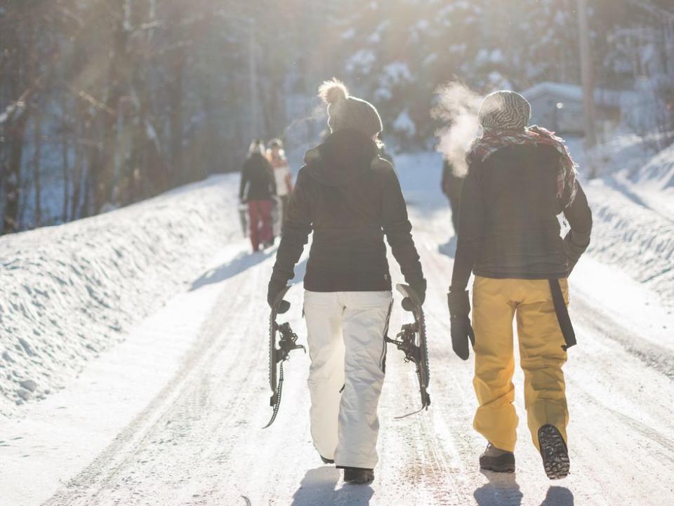 woman holding snow ski blades while walking on snowy mountain during daytime