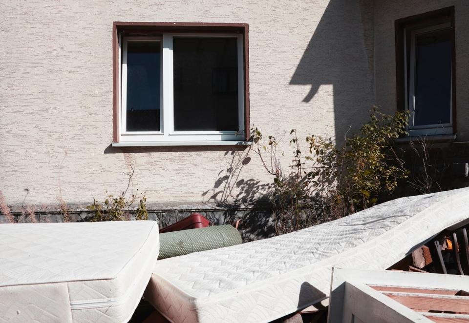 Mattresses are seen discarded in front of a home. 