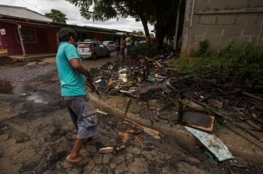 A man throws burnt debris from the house of opposition student leader Yubrank Suazo after it was burnt down amid the ongoing conflict in Nicaragua