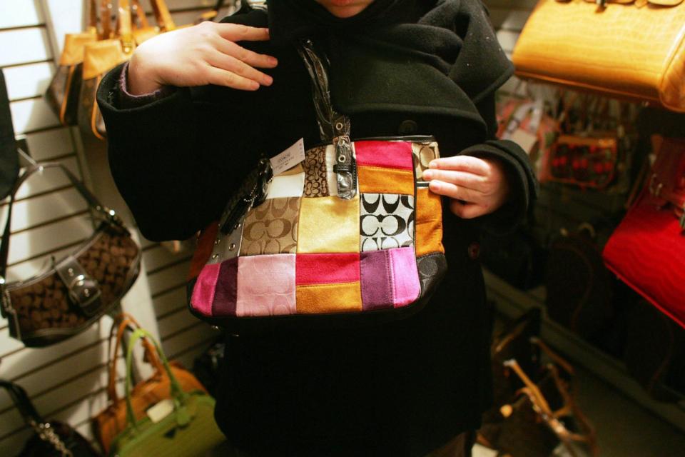 PHOTO: In this Feb. 1, 2006, file photo, an unidentified woman holds up a counterfeit Coach handbag in the back room of tourist shop in New York's Chinatown. (Bloomberg via Getty Images, FILE)