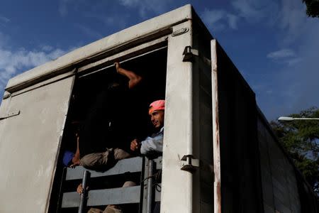 Commuters ride on a cargo truck used as public transportation in Valencia, Venezuela. REUTERS/Marco Bello