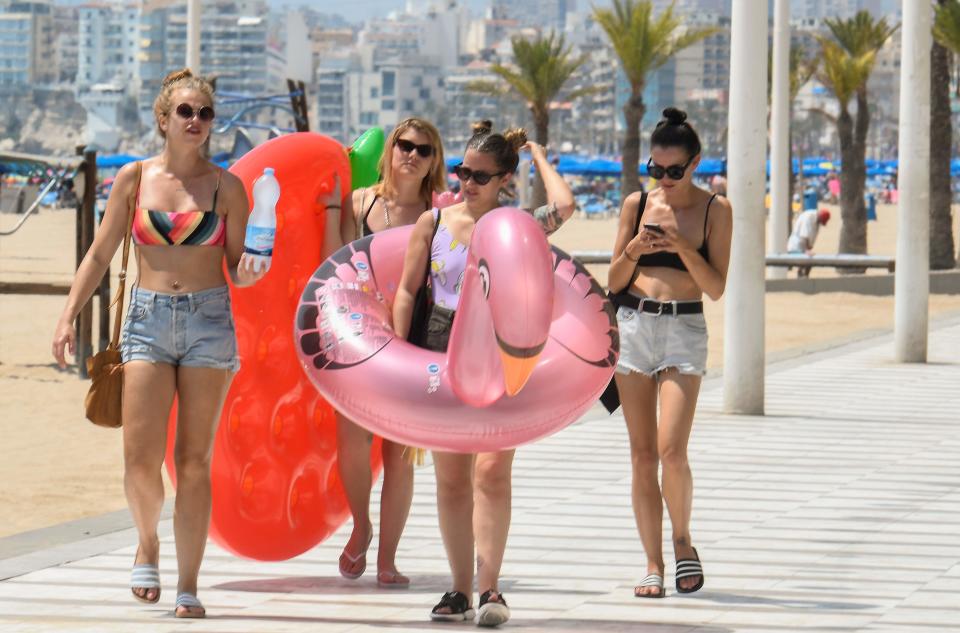 Some girls carry inflatables as they walk on the promenade of the seaside resort of Benidorm, on August 5, 2018 - Europe sweltered through an intense heatwave today, with soaring temperatures contributing to forest fires, nuclear plants closing and even threatening the Netherlands' supply of fries, although some countries experienced a slight respite. (Photo by JOSE JORDAN / AFP)        (Photo credit should read JOSE JORDAN/AFP/Getty Images)