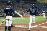 Tampa Bay Rays' Manuel Margot, right, heads to the dugout and is congratulated by Brandon Lowe after scoring during the first inning of the team's baseball game against the Detroit Tigers on Thursday, Sept. 16, 2021, in St. Petersburg, Fla. (AP Photo/Scott Audette)