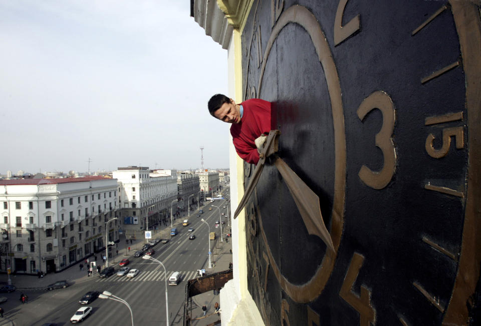 FILE - Technician Oleg Ryabtsev performs maintenance work on a clock in Minsk, Belarus, Saturday, March 29, 2008. Once again, most Americans will set their clocks forward by one hour this weekend, losing perhaps a bit of sleep but gaining more glorious sunlight in the evenings as the days warm into summer. There's been plenty of debate over the practice but about 70 countries — about 40 percent of those across the globe — currently use what Americans call daylight saving time. (AP Photo/Sergei Grits, File)