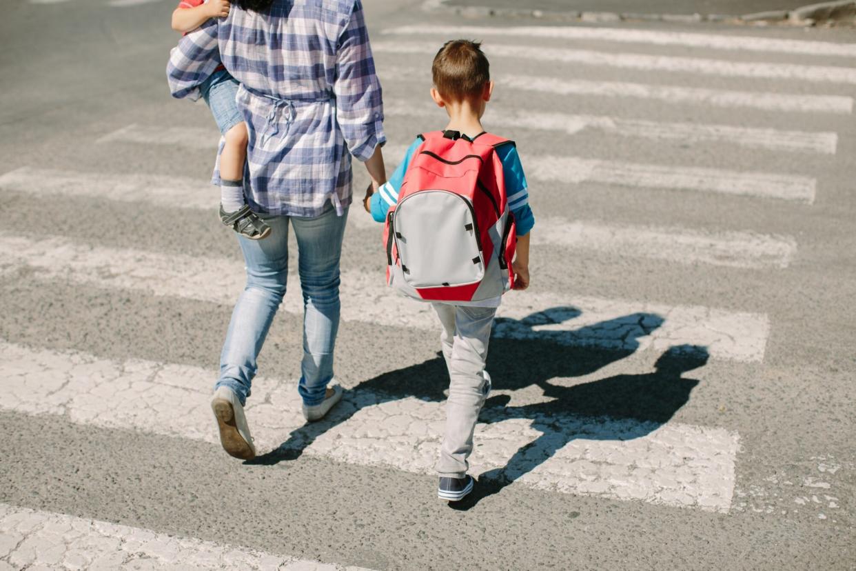 An image of a mother and her children crossing a road on the way to school.