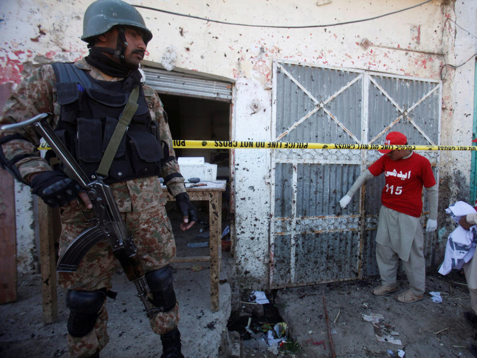 A soldier stands guard as voluteers collect remains of the walls and doors around the site of a blast at the courthouse in Charsadda, Pakistan, 21 February: Reuters