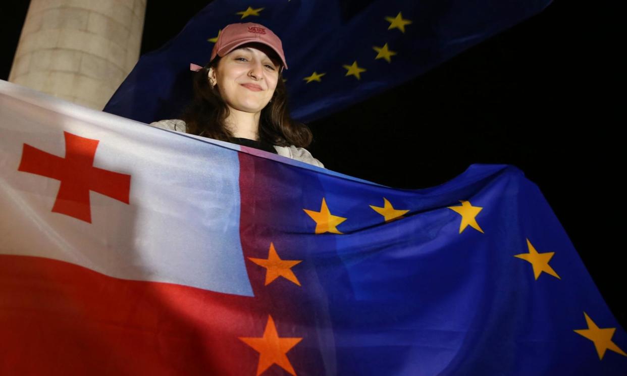 <span>A demonstrator holds the Georgian national and EU flags during an opposition protest in Tblisi on 3 May against ‘the Russian law’, which critics fear will stifle media freedom and endanger the country's bid for EU membership.</span><span>Photograph: Zurab Tsertsvadze/AP</span>