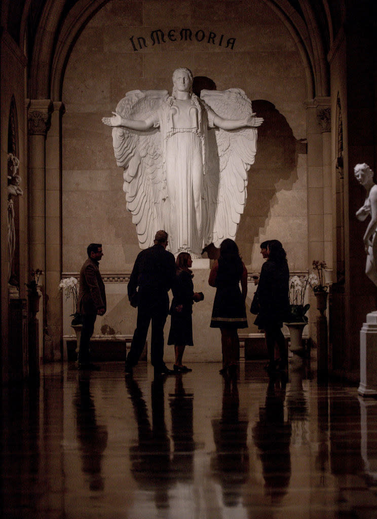 people stand before Elizabeth Taylor's burial site at Forest Lawn's Great Mausoleum, which has a large angel statue