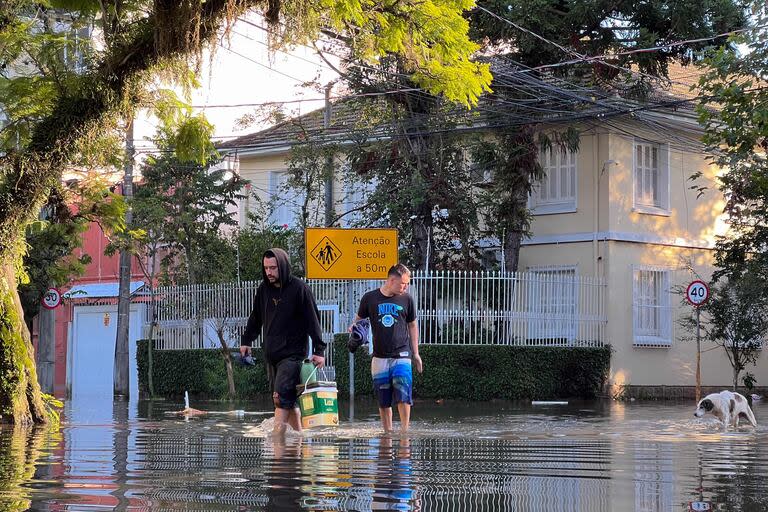 Dos personas caminan por calles inundadas del barrio Floresta de Porto Alegre