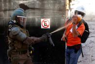 Un miembro de las fuerzas de seguridad usa gas pimienta contra un observador de derechos humanos durante una protesta contra el gobierno de Chile en Valparaíso, Chile