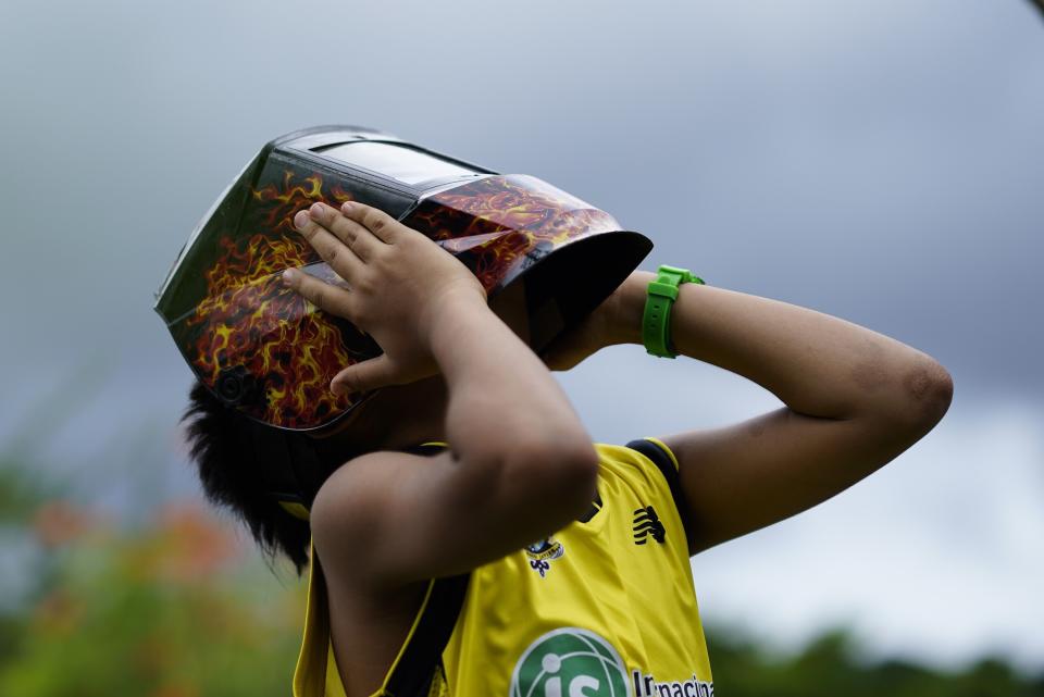 Un niño sostiene una máscara para proteger sus ojos mientras la gente se reúne para ver el eclipse anular solar del pasado 14 de octubre de 2023 (AP Foto/Arnulfo Franco)