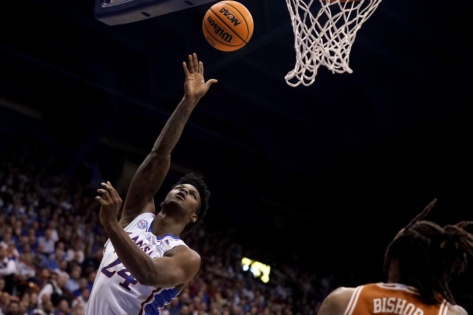 Kansas forward K.J. Adams Jr. (24) gets past Texas forward Christian Bishop to put up a shot during the first half of an NCAA college basketball game Monday, Feb. 6, 2023, in Lawrence, Kan. (AP Photo/Charlie Riedel)