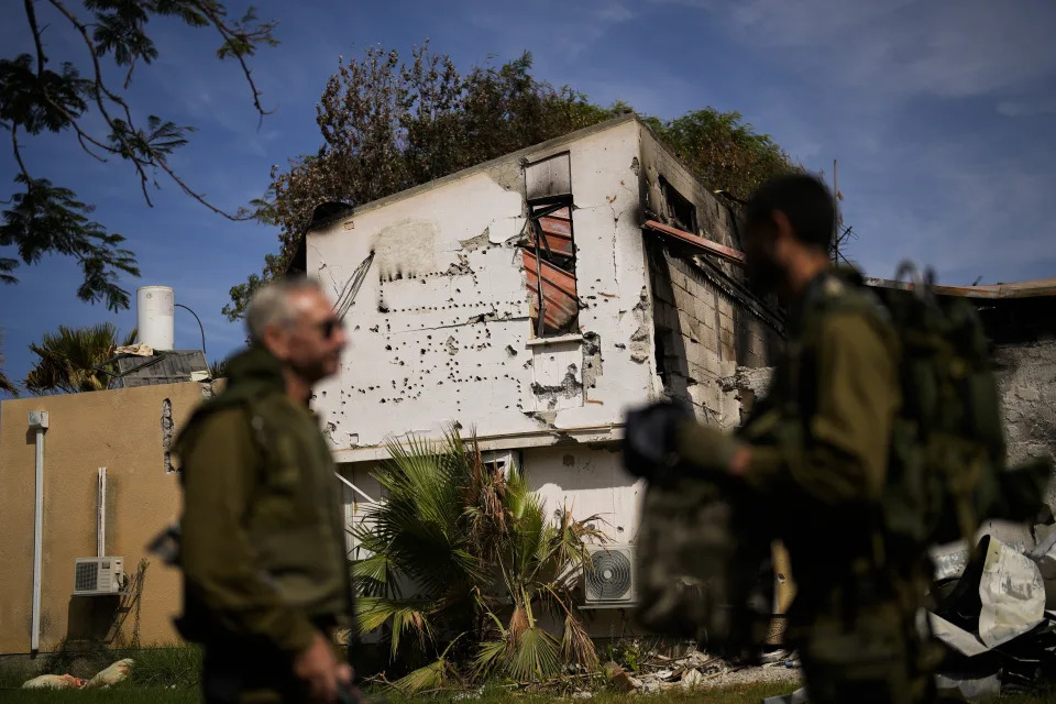 Soldiers walk next to a house damaged by Hamas militants at Kibbutz Kissufim in southern Israel, Saturday, Oct. 21, 2023. The Kibbutz was stormed by Hamas militants from the nearby Gaza Strip on Oct. 7, when they killed and captured many Israelis. (AP Photo/Francisco Seco)