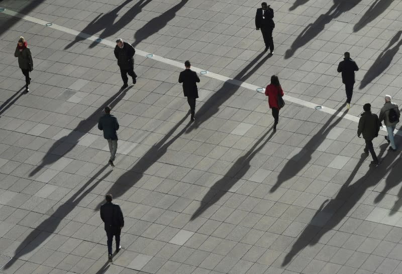 FILE PHOTO: People cast long shadows in the winter sunlight as they walk across a plaza in the Canary Wharf financial district of London, Britain, January 17, 2018. REUTERS/Dylan Martinez