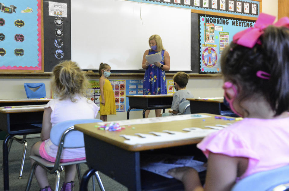 FILE - In this Aug. 27, 2020, file photo, Hadlee Yohn, back left, of Minersville, stands in front of the class as teacher Ashley Thompson, of Tremont, back right, reads information about Yohn during kindergarten orientation at St. Nicholas Ukrainian Catholic School in Minersville, Pa. Moves reflecting takeaways from pandemic experiences are being incorporated into many teacher preparation programs. Digital tools, online instruction, mental and emotional wellness are happening not just in what aspiring educators are learning, but how. More programs are using tools such as computer simulation training and virtual field supervision of student-teaching. (Lindsey Shuey/Republican-Herald via AP, File)