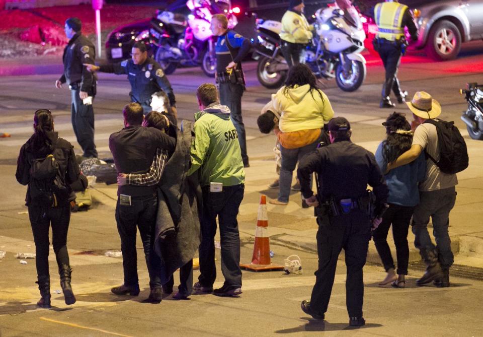 People walk away after the accident on Red River Street in downtown Austin, Texas, that left two dead at SXSW on Wednesday March 12, 2014. Police say a man and woman have been killed after a suspected drunken driver fleeing from arrest crashed through barricades set up for the South By Southwest festival and struck the pair and others on a crowded street. (AP Photo/Austin American-Statesman, Jay Janner)