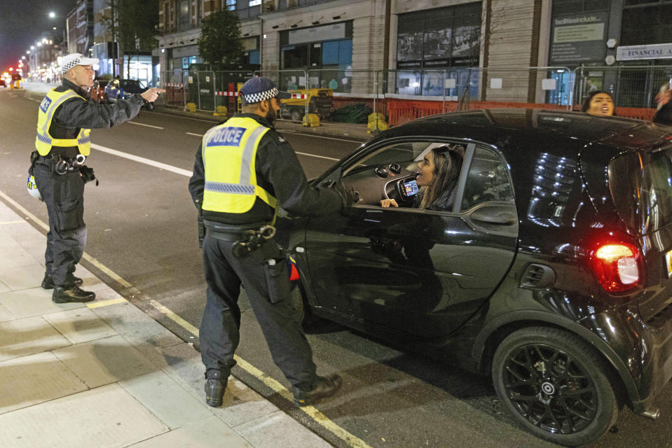 Two women are asked to leave the area by police after stopping to clash with protesters outside Kilburn Islamic Centre in London, Sunday, Sept. 25, 2022. The protesters were demonstrating against the death of Iranian Mahsa Amini, a 22-year-old woman, who died in Iran while in police custody, was arrested by Iran's morality police for allegedly violating its strictly-enforced dress code. (David Parry/PA via AP)