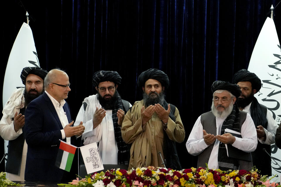 Mullah Abdul Ghani Baradar, Acting Deputy Prime Minister of the Afghan Taliban's caretaker government, center, and the chief financial officer of GAAC Solutions, Razack Aslam Mohammed Abdur Razack, second left, join others in a prayer during a document signing ceremony in Kabul, Afghanistan, Tuesday, May 24, 2022. The Taliban said Tuesday that they've signed a deal allowing Abu Dhabi-based GAAC Solutions to manage the airports in Herat, Kabul and Kandahar. (AP Photo/Ebrahim Noroozi)