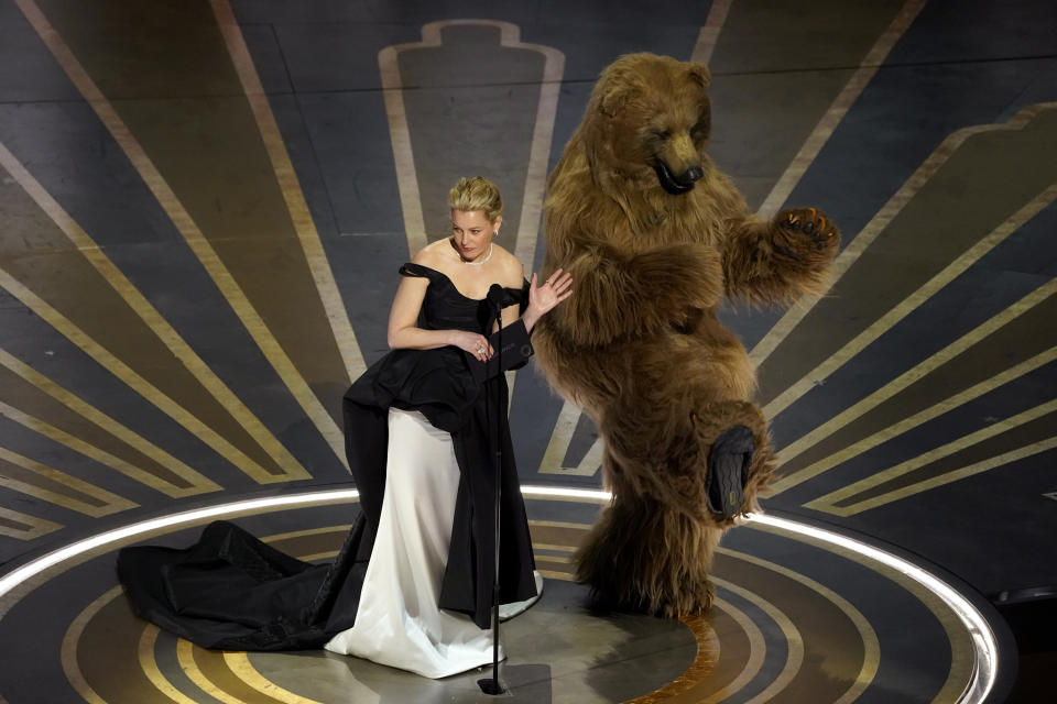 Elizabeth Banks, left, and an actor dressed in a costume from her movie "Cocaine Bear" present the award for best visual effects at the Oscars on Sunday, March 12, 2023, at the Dolby Theatre in Los Angeles. (AP Photo/Chris Pizzello)