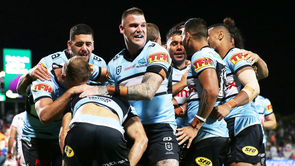 The Sharks (pictured) celebrate a try against the Dragons.