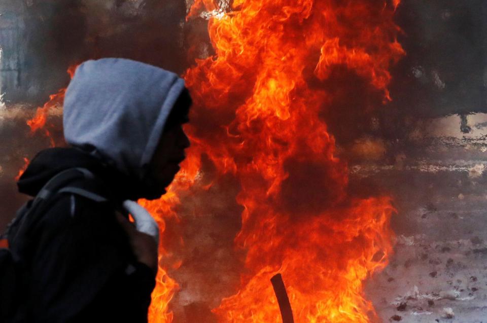 Una persona cerca de las llamas en las protestas de Chile de octubre de 2019