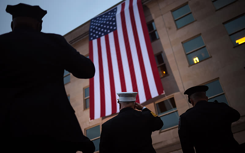 First responders watch as an American flag is unfurled during a Sept. 11 ceremony observing the 9/11 terrorist attacks at the Pentagon in Arlington, Va. The Defense Department held a remembrance ceremony for the 184 lives lost in the 2001 terrorist attack on the Pentagon. <em>Win McNamee/Getty Images</em>