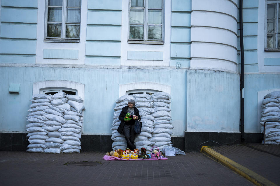 A woman sells toys in front of a building with windows protected by sandbags in Kyiv, Ukraine, Sunday, April 28, 2024. (AP Photo/Francisco Seco)