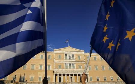 Protesters hold an EU flag and a Greek flag (L) as people gather at the entrance of the Greek parliament, during a rally calling on the government to clinch a deal with its international creditors and secure Greece's future in the Eurozone, in Athens June 18, 2015. REUTERS/Yannis Behrakis