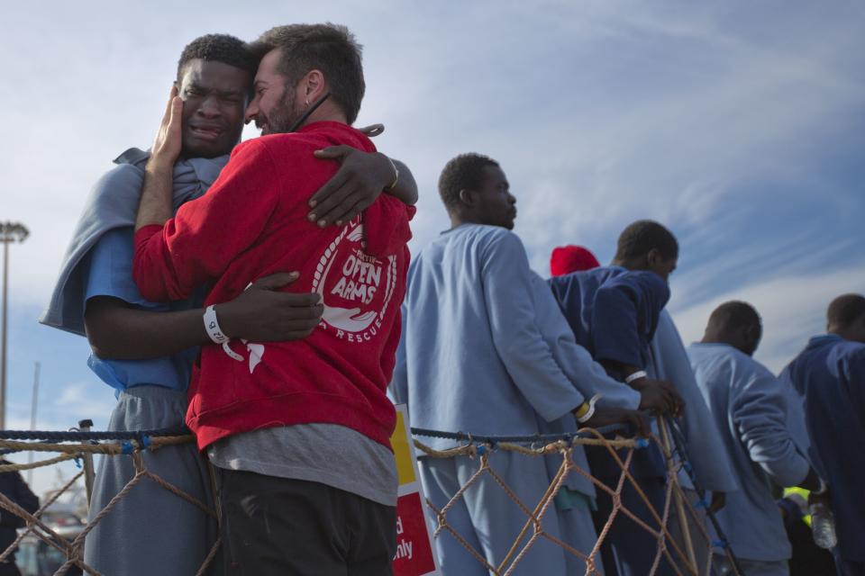 FILE - In this Sunday, Feb. 5, 2017 file photo, Kybumba Fran, 25, from Cameroon, cries with the head of the mission of Proactive Open Arms NGO Riccardo Gatti, from Italy, as he leaves the Golfo Azzurro rescue vessel after arriving at the port of Pozzallo, south of Sicily, Italy, with more than 220 migrants aboard the ship rescued at the Mediterranean sea. Spanish aid groups say Spain is allowing them to deliver aid supplies to refugee camps in Greek islands, but they face hefty fines if their boats venture into official search and rescue areas in the Central Mediterranean. (AP Photo/Emilio Morenatti, File)